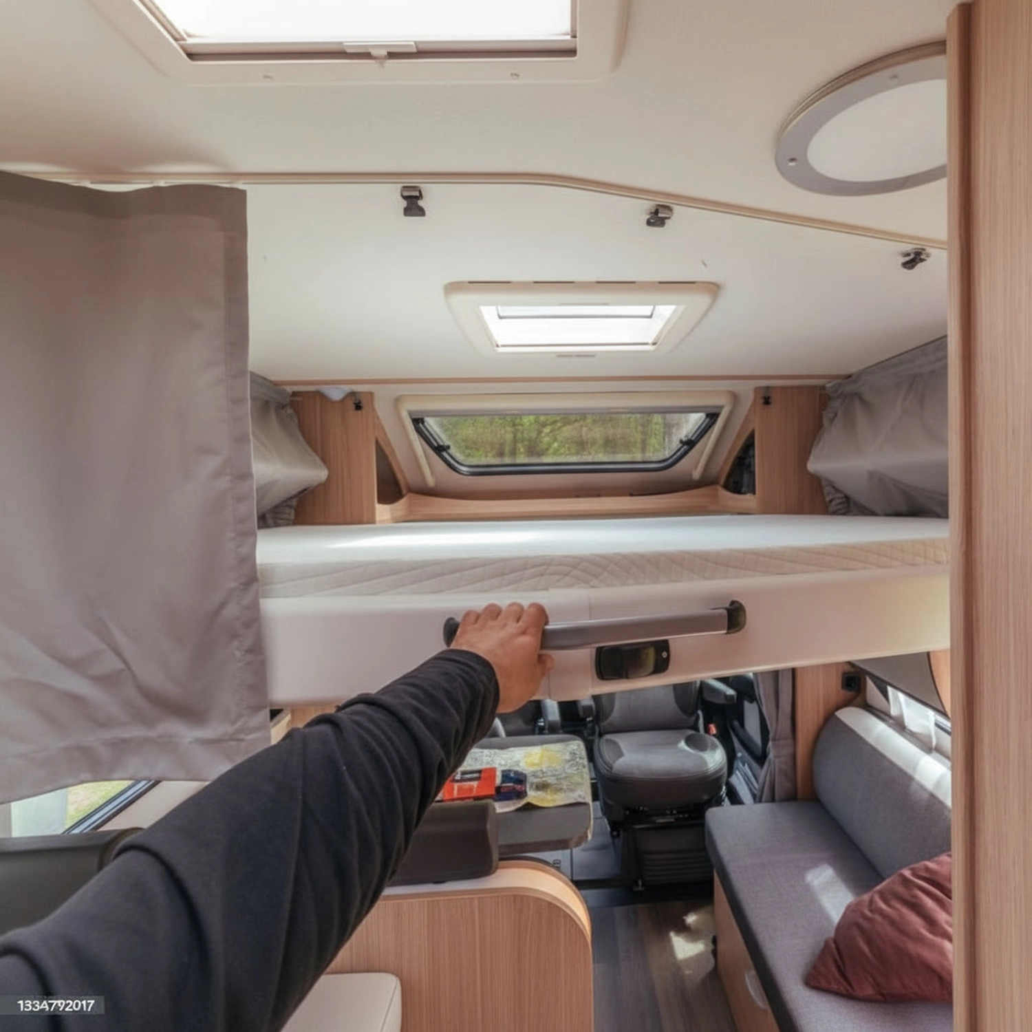 Mobiler Gasservice und Serviceleistung - serviceleistungen rund um Wohnmobil und Wohnwagen – Innenraum eines Wohnmobils mit einer Person, die ein Etagenbett über dem Sitz- und Fahrbereich absenkt
